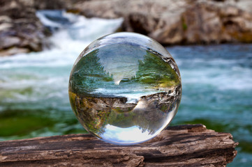 Crystal glass ball sphere reveals waterfall landscape with spherical perspective