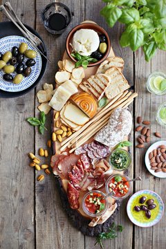 
    Mediterranean appetizers table concept. Dinner table with tapas selection: cured meat and salami, gazpacho soup, jamon, olives, cheese, hummus and vegetables. Overhead view.
