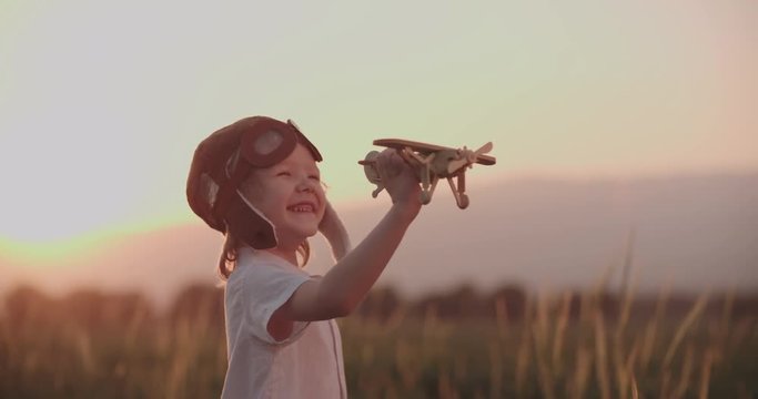 close-up shot of happy boy with toy airplane in wheat field running. dream, childhood, memories concept.Slow motion, sunset time.
