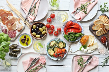 
    Mediterranean appetizers table concept. Dinner table with tapas selection: cured meat and salami, gazpacho soup, jamon, olives, cheese, hummus and vegetables. Overhead view.