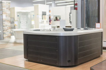 Square bathtub with relaxing bubble bath foam in the building store. baths in the plumbing store. Sanitary engineering shop. White bathrooms. Corner bathtup in the building store