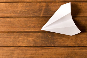 White paper airplane on wooden background. Travel concept