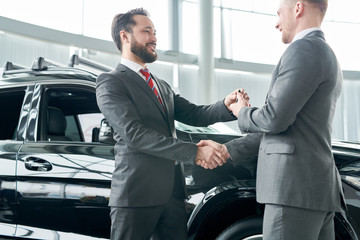 Salesman giving the key from new car to his client