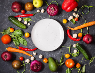 Fresh organic vegetables and seasoning ingredients for tasty vegetarian cooking around plate