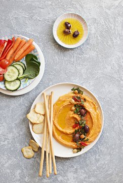 Hummus. Sweet potato, pumpkin or carrot Hummus served with fresh vegetables, seasoned with olives, herbs, extra virgin olive oil and paprika. Overhead view, copy space