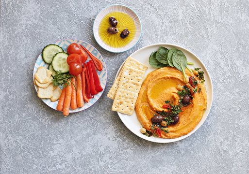 Hummus. Sweet potato, pumpkin or carrot Hummus served with fresh vegetables, seasoned with olives, herbs, extra virgin olive oil and paprika. Overhead view, copy space