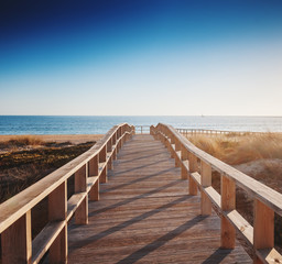 Obraz premium drewniana ścieżka do morza o zachodzie słońca, piękny krajobraz, Algarve, Portugalia