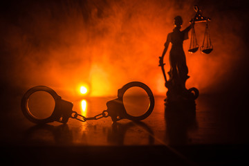 Legal law concept. Silhouette of handcuffs with The Statue of Justice on backside with the flashing...