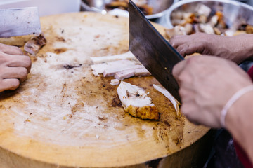 Chef cut crispy belly pork on chopping board.