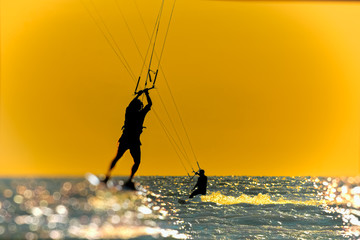 Naklejka premium Silhouette of kitesurfer on sunset sky background, toned