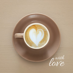 image of coffe cup with foam of heart shape over wooden background and text: WITH LOVE.