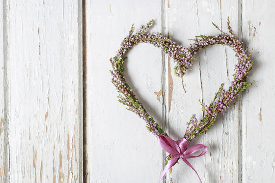 Heather (erica) door wreath in heart shape on wooden background