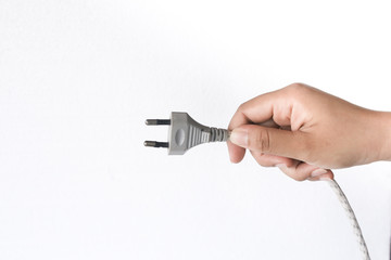 Close up hand inserting an electrical plug into a wall socket