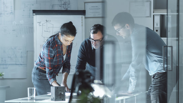 Team of Design Engineers Work on a Project. They Work on a Illuminated Conference Table with Documents, Blueprints and Laptop on it.