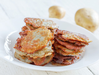 fresh homemade hash Browns and raw potatoes on a close-up plate