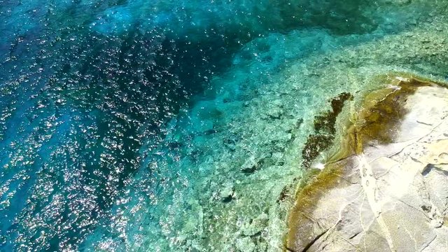 Blue ocean water with wave and rocks filmed above