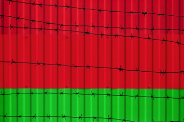 National flag of Belarus on fence. Barbed wire in the foreground symbolizes entry ban or prohibition for crossing border of country