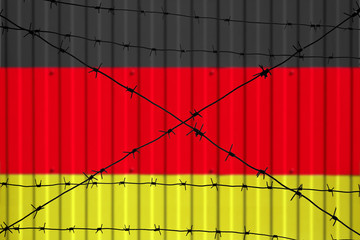 National flag of Germany on fence. Barbed wire in the foreground symbolizes entry ban or prohibition for crossing border of country