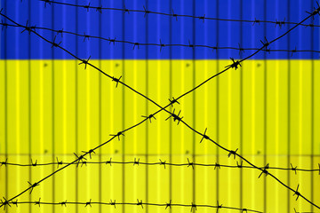National flag of Ukraine on fence. Barbed wire in the foreground symbolizes entry ban or prohibition for crossing border of country