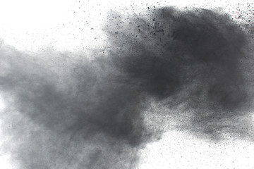Black powder explosion against white background.Closeup of black dust particles explode isolated on...