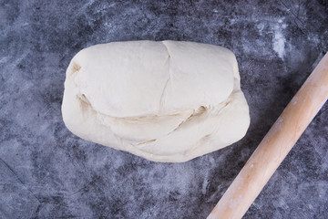 Fresh dough on the table with flour, and rolling pin