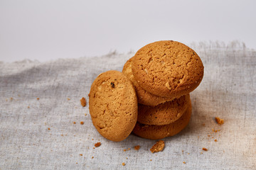 Pile of oat cookies on homespun napkin, close-up, selective focus.