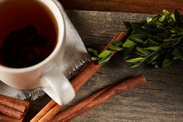 Traditional Christmas tea concept with a cup of hot tea, cookies and decorations on a wooden table, selective focus