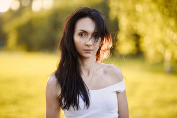 close-up portrait of a beautiful cute girl in a romantic brunette skirt with in a green garden posing and smiling