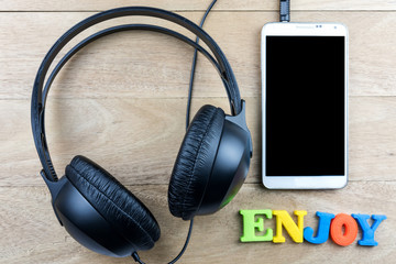 Black headphones and smartphone on wooden background