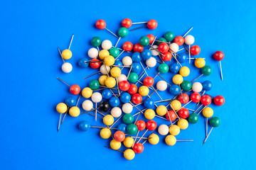 Office supplies in the form of colored buttons and paper clips on blue background.