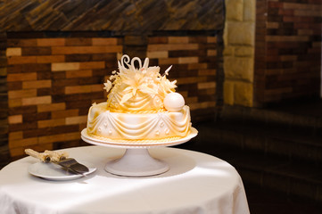 A white wedding cake decorated with gold flowers and white swans. 