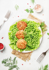 Fish meatballs or cutlets from sea cod with green vegetables, top view