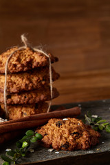 Christmas composition with chocolate biscuits, cinnamon and dried oranges on wooden background, close-up.