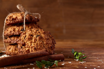 Christmas composition with chocolate biscuits, cinnamon and dried oranges on wooden background, close-up.