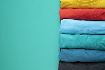 close up of rolled colorful clothes on green background - obrazy, fototapety, plakaty