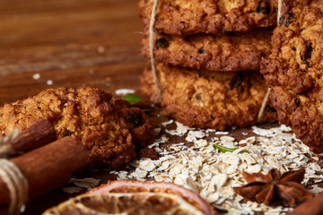 Christmas composition with chocolate biscuits, cinnamon and dried oranges on wooden background, close-up.