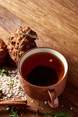 Christmas teatime with oatmeal, chocolate biscuits, and spices, on wooden background, close-up, selective focus.