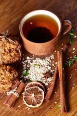 Christmas teatime with oatmeal, chocolate biscuits, and spices, on wooden background, close-up, selective focus.