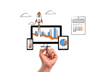  woman hand with pencil draws Rocket launch from PC monitor. PC monitor and tablet and smart phone width business chart on office desk. Concept of business start-up, boost or success