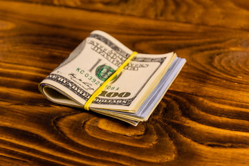 Bunch of the one hundred dollar bills with rubber on wooden table