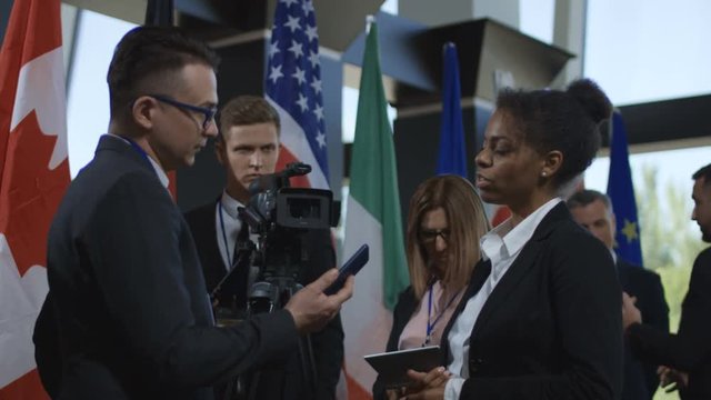 Formal African-American woman talking to journalist for camera and giving interview on international summit