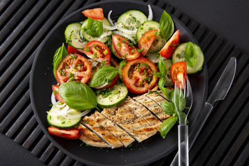 Vegetable salad and grilled chicken on a black background. Healthy food. Diet.