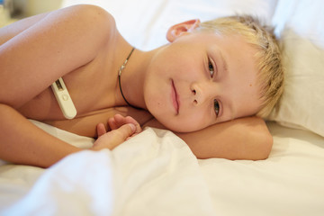 Obraz na płótnie Canvas boy measures the temperature on the bed