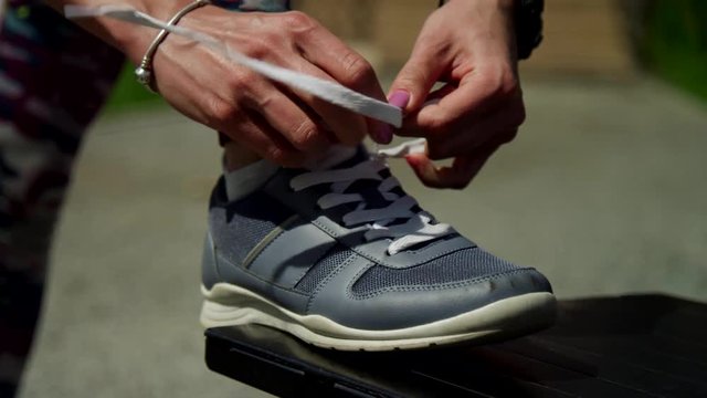 Young athletic girl getting ready for a jog. Ties shoelaces