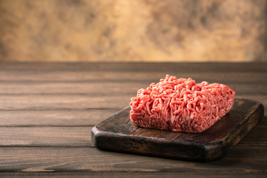 Fresh raw beef minced meat on dark wooden board. Healthy food ingredients concept with copy space.