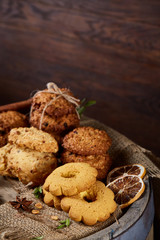 Conceptual composition with assortment of cookies and cinnamon on a wooden barrel, selective focus, close-up