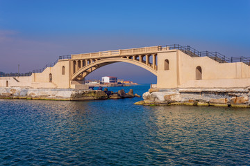 Obraz premium Bridge in the sea at Montazah park with calm sea and clear sky at sunrise time, Alexandria, Egypt