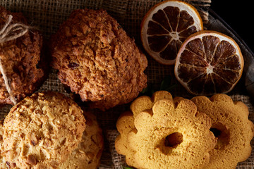 Conceptual composition with assortment of cookies and cinnamon on a wooden barrel, selective focus, close-up