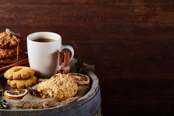 White porcelain mug of tea and sweet cookies on wooden background, top view, selective focus