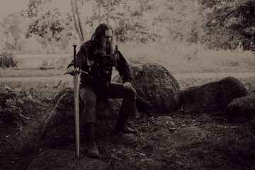 Knight in the forest. Guy in medieval costume with sword. effect of toning